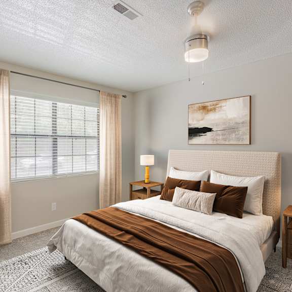 A bedroom with a large bed, a nightstand, and a window with curtains.
