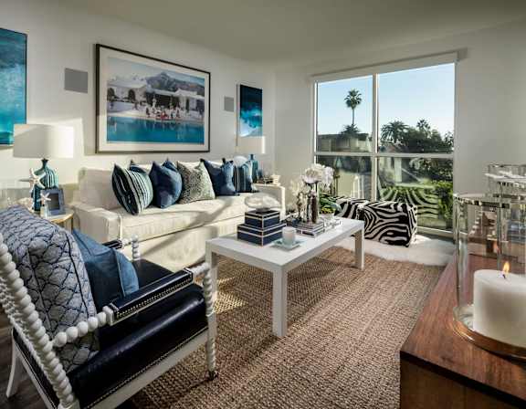A living room with a white sofa and a large window.at Chelsea Santa Monica, Santa Monica California