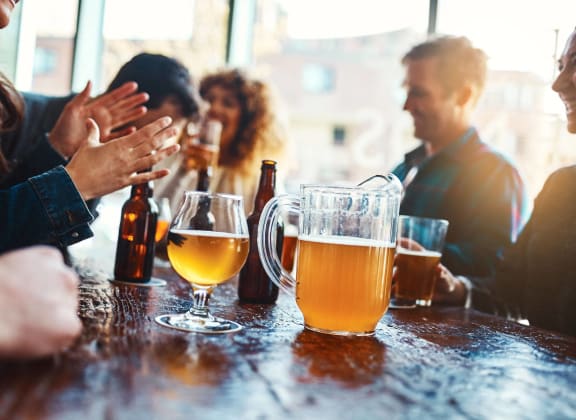 a group of people sitting at a bar with beers