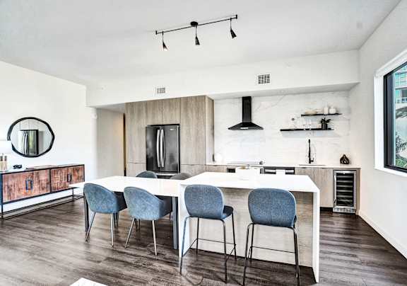 A modern kitchen with a white table and blue chairs.