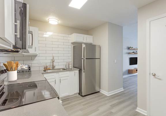 A kitchen with a refrigerator, stove, and sink.