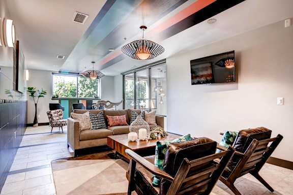 A modern living room with a wooden sofa set and a TV mounted on the wall.