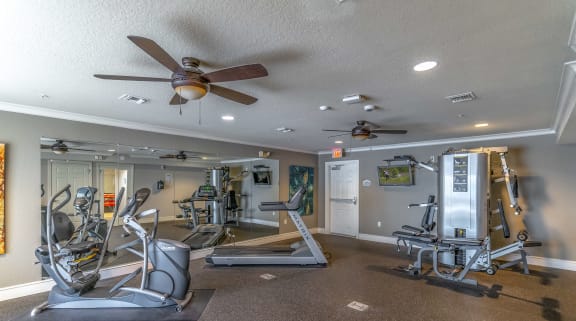 a home gym with exercise equipment and a ceiling fan