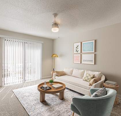 A living room with a white couch, a green armchair, a wooden coffee table, and a potted plant.