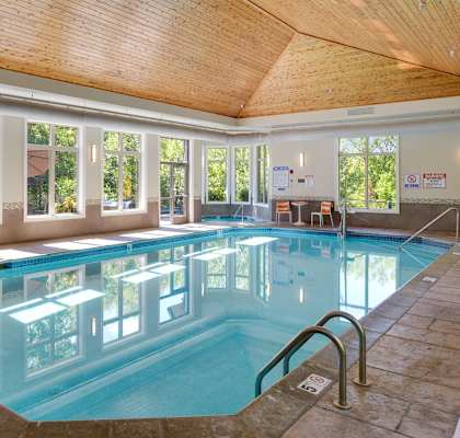 a swimming pool with a wooden ceiling and windows around it