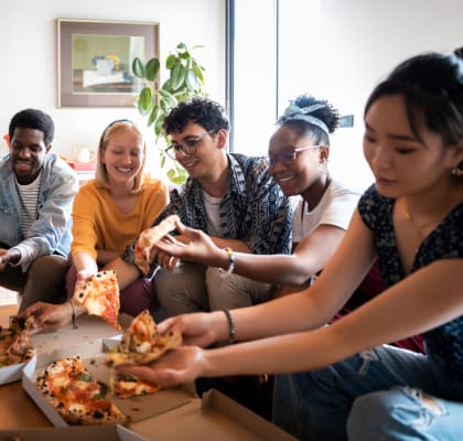 a group of people sitting around a table eating pizza