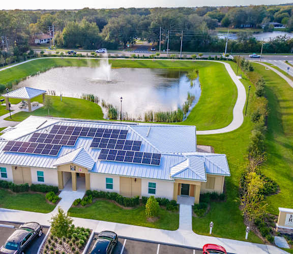 an aerial view of a building with solar panels on the roof and a fountain in the background