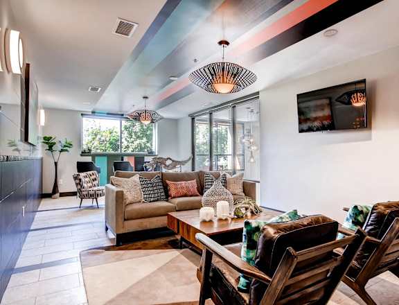 A modern living room with a wooden sofa set and a TV mounted on the wall.