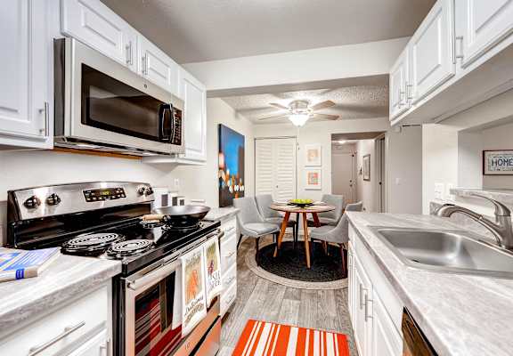 view of kitchen and dining room with stainless steel appliances and white cabinets