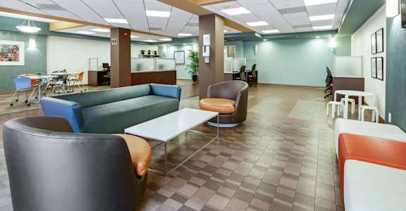 A modern office lounge with blue and grey chairs and a white table.at 6940 Sepulveda, Van Nuys, CA