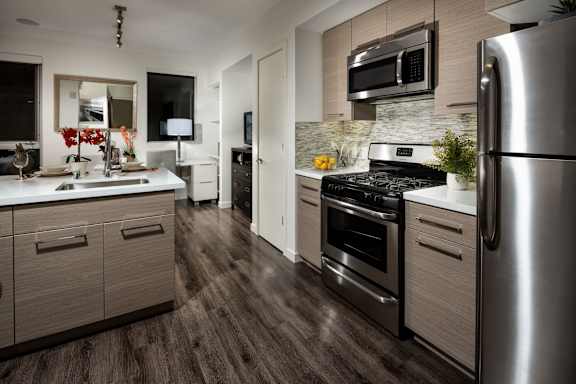 A modern kitchen with a stainless steel refrigerator and dark wood flooring.at Chelsea Santa Monica, Santa Monica, CA 90411