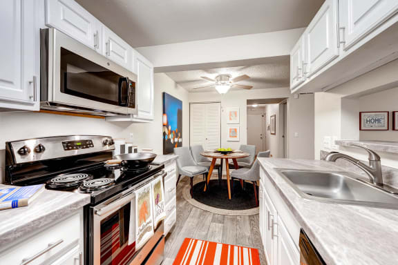 view of kitchen and dining room with stainless steel appliances and white cabinets