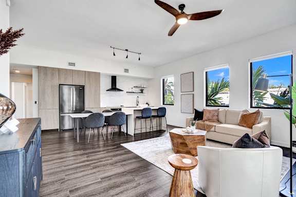 A modern living room with a kitchen area in the background.