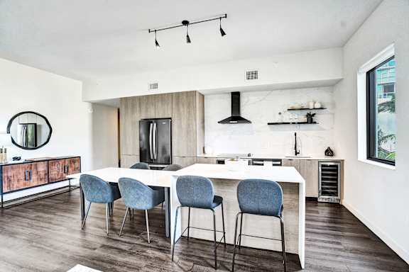 A modern kitchen with a white table and blue chairs.