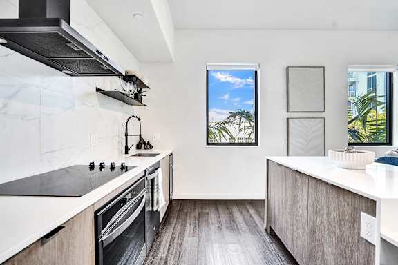 A modern kitchen with a stove top oven and a window.