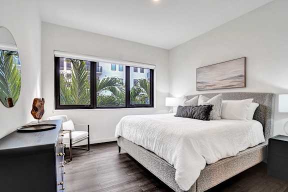 A bedroom with a large bed and a window overlooking a green landscape.