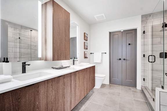 A modern bathroom with a wooden vanity and a walk-in shower.