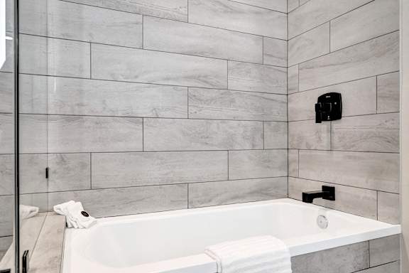 A white bathtub with a towel and a toilet brush on the side.
