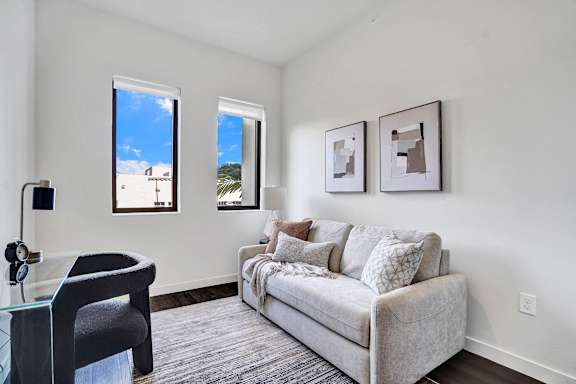A living room with a grey couch and a glass table.