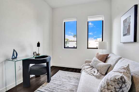 A living room with a grey couch and a glass table.