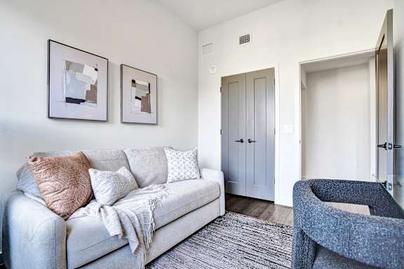 A living room with a grey couch and two framed pictures on the wall.