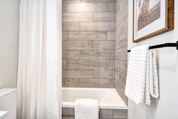 A white towel hangs on a black rack in a bathroom.