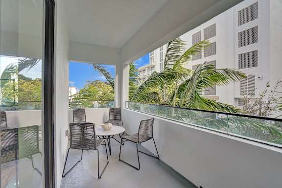 A balcony with a table and chairs overlooking a lush green landscape.