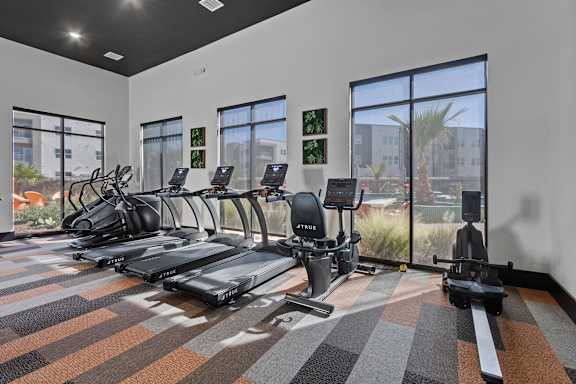 A gym with treadmills, exercise bikes, and a rowing machine.