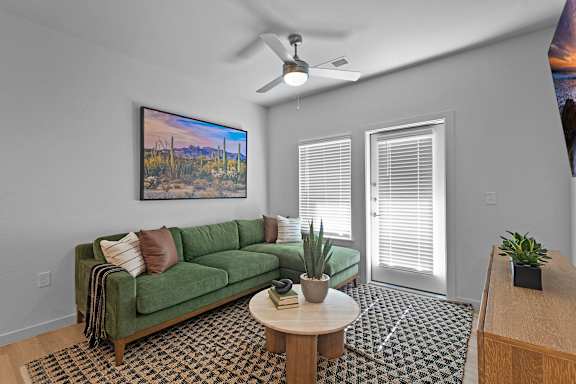 A living room with a green couch and a painting on the wall.