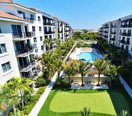 A view of a luxury apartment complex with a pool and palm trees.