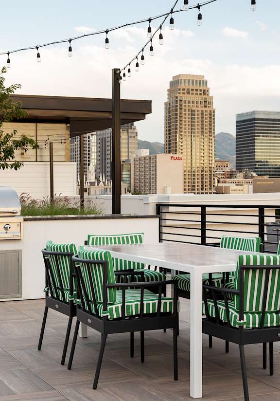 A patio with a table and chairs overlooking a city skyline.