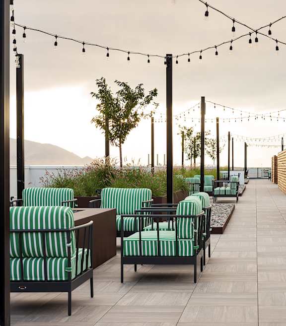 A patio with green striped chairs and wooden tables.