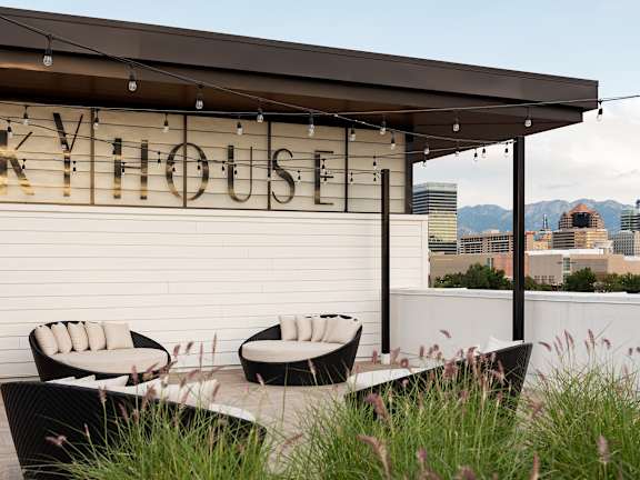 A patio area with a table and chairs in front of a building with the name "SKYHOUSE" on it.