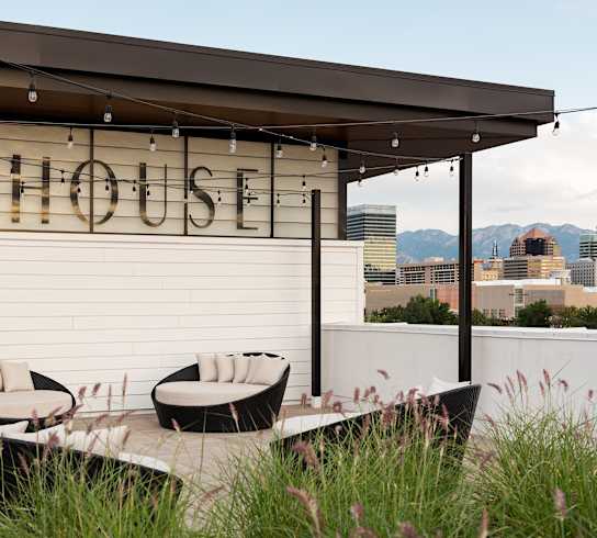A patio area with a table and chairs in front of a building with the name "SKYHOUSE" on it.