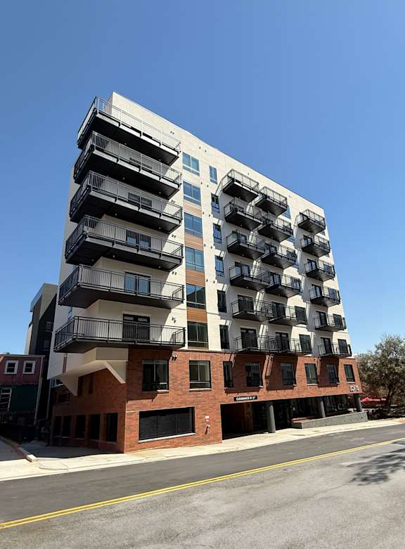 A modern multi-story building with balconies on the upper floors.