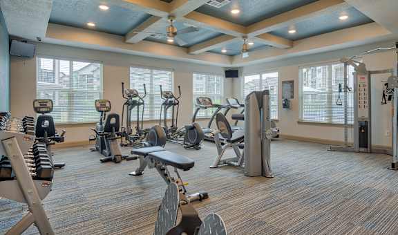 a gym with various exercise equipment in a room with windows