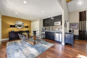 Kitchen Area with Wood Inspired Floors, Rug, Rectangular Glass Table, Dishwasher, Dryer, Dark Wood Inspired Cabinets, Mounted Microwave, Dressers with 2 Lamps