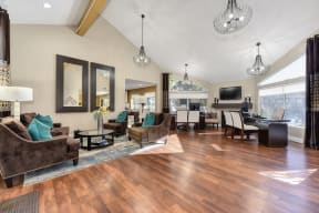 Leasing Office Wide View of Wood Inspired Floors, 4 Cushioned Chairs, 2 Long Mirrors, Rug, 3 Hanging Ceiling Lights, Open View Windows, and Desks and Chair