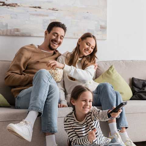 A family of six is sitting on the floor in their living room.