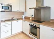 Thumbnail 3 of 5 - a kitchen with white cabinets and a stove and a microwave