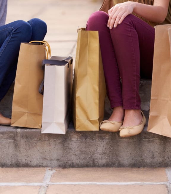 Two people sitting on a ledge with shopping bags. at Woodlands Creekside Apartments, Georgia, 30253