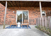 Thumbnail 8 of 8 - A red brick house with a white door and a blue rug in front.