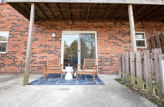 A red brick house with a white door and a blue rug in front.