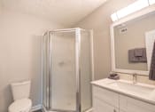 Thumbnail 5 of 8 - A white bathroom with a toilet, sink, and shower.