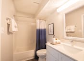 Thumbnail 6 of 8 - A white bathroom with a toilet, sink, and bathtub.