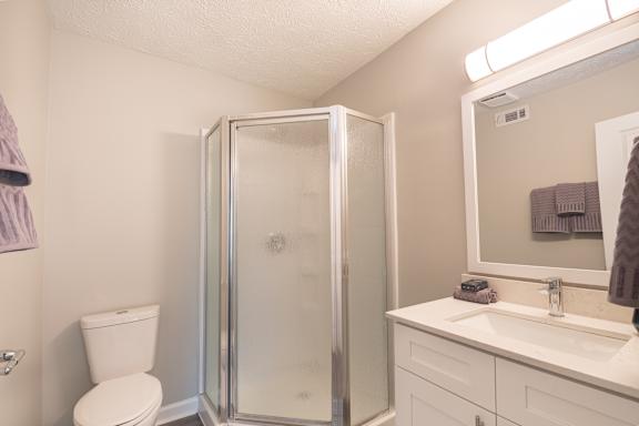 A white bathroom with a toilet, sink, and shower.