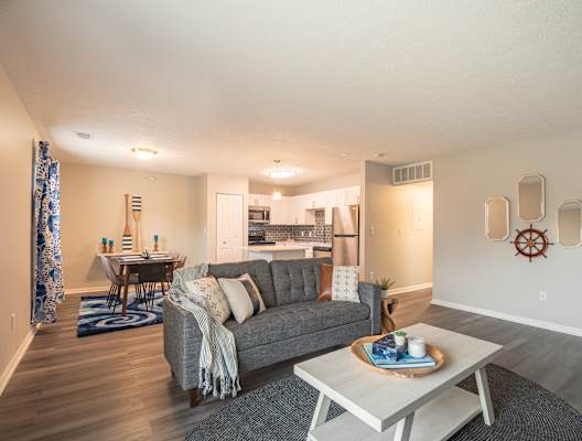 a living room with a couch coffee table and a kitchen in the background