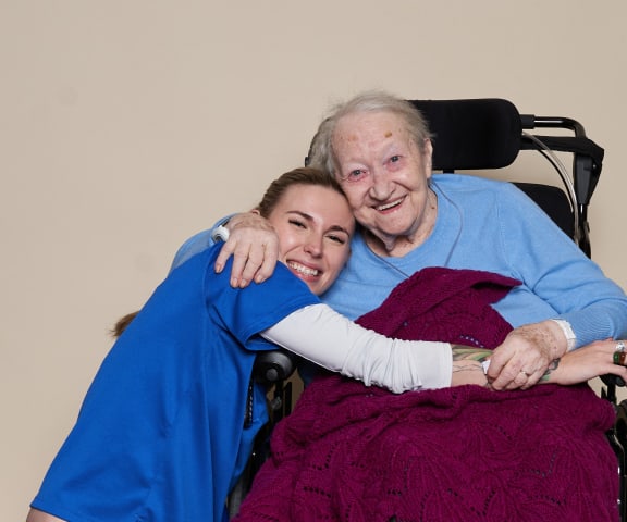 a woman hugging an elderly patient in a wheelchair