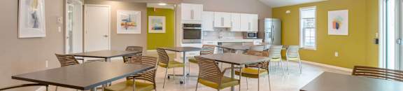 a dining room with tables and chairs and a kitchen at Station Pointe, Mansfield, 02048