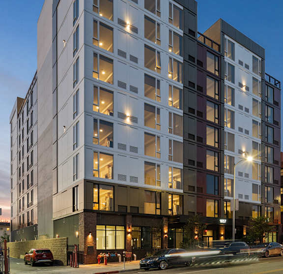 A modern multi-story building with a lot of windows and lights on.